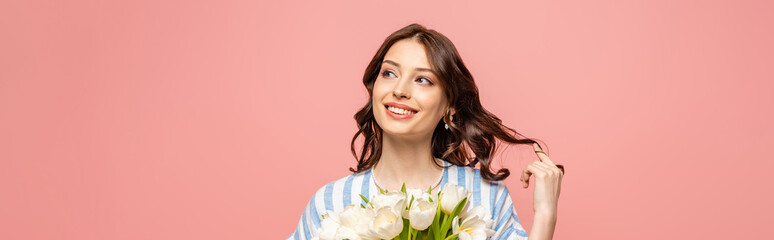 panoramic shot of cheerful girl touching hair while holding bouquet of white tulips isolated on pink - Powered by Adobe