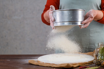 Woman cook sifts the sieve flour on the table. Frozen motion