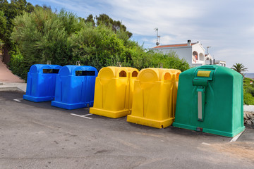 A row of colorful dustbins for waste segregation.