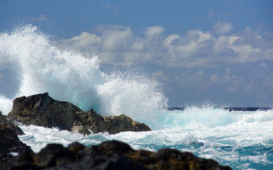 Fototapeta na wymiar Big waves beating against rock shore of Sao Miguel island, Azores. Water splash, background of blue ocean, cloudy sky