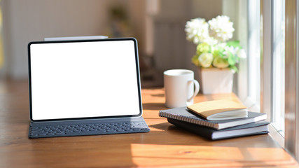 Laptop with a notebook and coffee on a wooden table in the office with beautiful lighting.