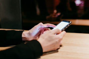 close up view of young woman using mobile phone in a cafe or restaurant indoors. Unrecognizable person lifestyles