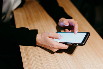 close up view of young woman using mobile phone in a cafe or restaurant indoors. Unrecognizable person lifestyles