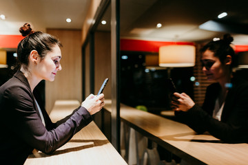 young woman using mobile phone in a cafe or restaurant indoors. Technology and lifestyle