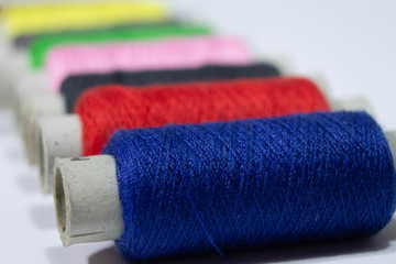 multi-colored spools of thread on a white background
