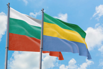 Gabon and Bulgaria flags waving in the wind against white cloudy blue sky together. Diplomacy...