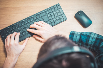 Workspace media concept: Black wireless headphones, keyboard and mouse on wooden desk