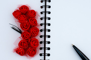lots of red roses tied together lie on a notepad with a handle