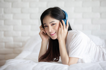 Beautiful Attractive Asian young woman listen music and lying on bed in bedroom feeling so relax and comfortable,Selective Focus