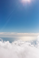Beautiful vertical photography aerial view at sunny peaceful surface of sea water and white fluffy clouds in clear blue sky as seen from mountain in 2000 metres high. Amazing idyllic photo background.