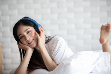 Beautiful Attractive Asian young woman listen music and lying on bed in bedroom feeling so relax and comfortable,Selective Focus