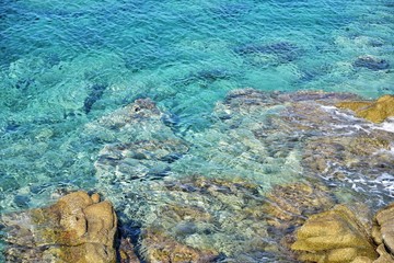 Seascape of rocky beach with azure sea water in sunny day. Amazing natural beach with white stones and turquoise water. crystal clear sea with sun reflection. Halkidiki Greece Blue Flag Beach