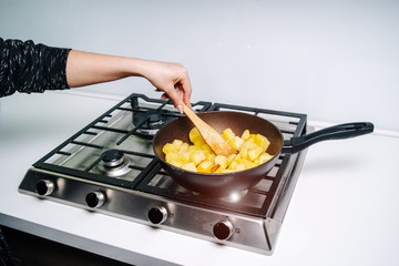 A woman frying potatoes in the kitchen. Fried potato wedges