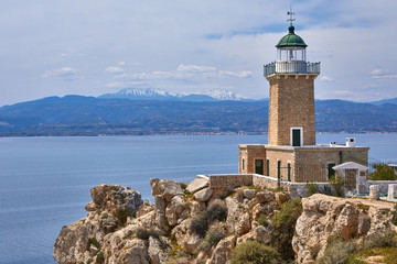 Melagkavi Lighthouse also known as Cape Ireon Light perching high on a headland overlooking eastern Gulf of Corinth, Greece. Bright sunny view of spring seascape, Cape Melagavi.