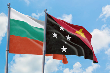 Papua New Guinea and Bulgaria flags waving in the wind against white cloudy blue sky together. Diplomacy concept, international relations.