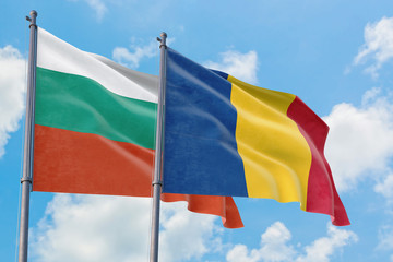 Romania and Bulgaria flags waving in the wind against white cloudy blue sky together. Diplomacy concept, international relations.