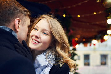Fototapeta na wymiar closeup portrait of attractive blonde woman embracing her boyfriend with smile on festive decorations background.
