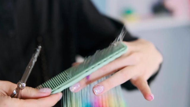 The hairdresser cuts dyed hair female client with scissors. A short pixie haircut and shaved temples . Ornament on the hair.