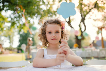 Fototapeta premium Small girl sitting outdoors in garden in summer, birthday celebration concept.