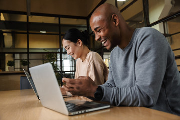 Image of multiethnic young coworkers working on laptops in office
