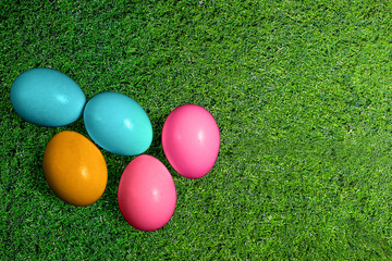 Fototapeta na wymiar Easter eggs on green grass background. Multicolor Easter symbol eggs flat lay top view with copy space. Seasonal spring holiday decoration