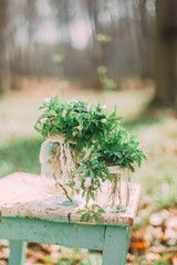 Bouquet of white spring flowers in Glass Jar On wooden chair in the forest outdoors