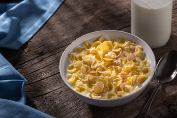 Breakfast with cereal. Flakes with milk. A plate of cereal with milk on a old wooden table. Perfect for breakfast. Free space for text.