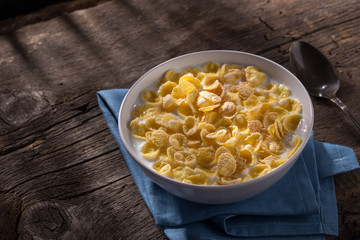 Breakfast with cereal. Flakes with milk. A plate of cereal with milk on a old wooden table. Perfect for breakfast. Free space for text.