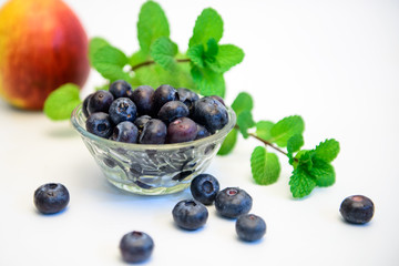 Still life photos of blueberries and green leaves on a white background.