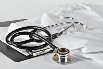 Black stethoscope on white medical gown. Black folder near medical equipment. Plastic folder with...