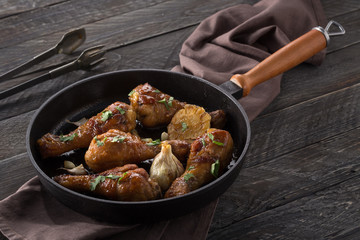 Chicken thighs with grilled vegetables. Chicken served in a frying pan on an old wooden table. Chicken with lime, zucchini, eggplants, onions and garlic. Close-up shot. Free space for text.