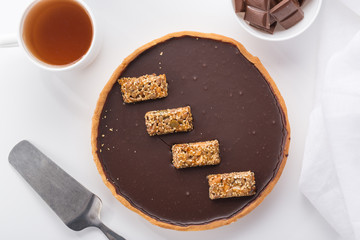 A cake with chocolate and nuts. Served on a white table with tea and a white napkin. Homemade cake on white background.