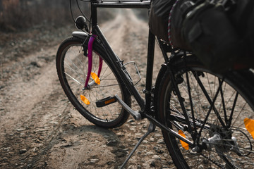 Outdoor close up view on bicycle with things, a tent on the trunk.. hilltop overlooking a valley in haze, a city on the horizon. winter or autumn landscape dirt road.