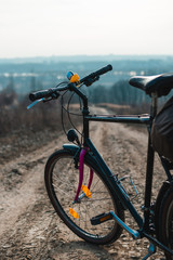 Fototapeta na wymiar Outdoor view on classic bicycle detail. hilltop overlooking a valley in haze, a city on the horizon. winter or autumn landscape dirt road. rubber duck on the steering wheel, vertical photo