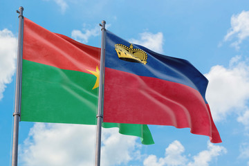 Fototapeta na wymiar Liechtenstein and Burkina Faso flags waving in the wind against white cloudy blue sky together. Diplomacy concept, international relations.