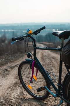 Outdoor view on classic bicycle detail. hilltop overlooking a valley in haze, a city on the horizon. winter or autumn landscape dirt road. rubber duck on the steering wheel, vertical photo
