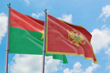 Montenegro and Burkina Faso flags waving in the wind against white cloudy blue sky together. Diplomacy concept, international relations.