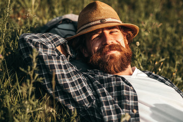 Bearded traveler chewing straw white resting on grass