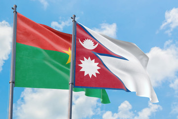 Nepal and Burkina Faso flags waving in the wind against white cloudy blue sky together. Diplomacy concept, international relations.