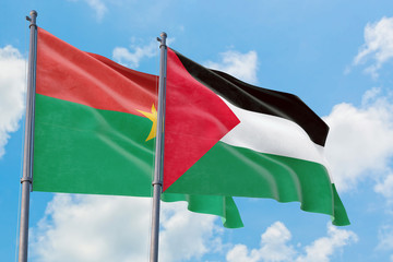 Palestine and Burkina Faso flags waving in the wind against white cloudy blue sky together....