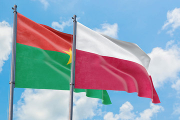 Poland and Burkina Faso flags waving in the wind against white cloudy blue sky together. Diplomacy concept, international relations.