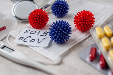 Medical face mask, stethoscope, pills and digital thermometer with inscription Wuhan coronavirus 2019-nCoV on the white table background. Novel coronavirus 2019-nCoV concept.
