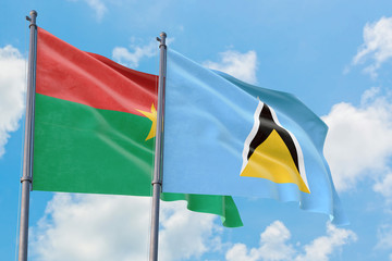 Saint Lucia and Burkina Faso flags waving in the wind against white cloudy blue sky together. Diplomacy concept, international relations.