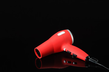 Red hair dryer on the black mirror background