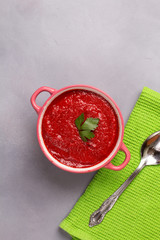 Tomato soup with parsley, onion and garlic on gray background. Comfortable food. Rustic style. Copy space. .