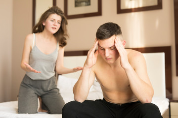 Young couple sitting on bed and quarreling in morning