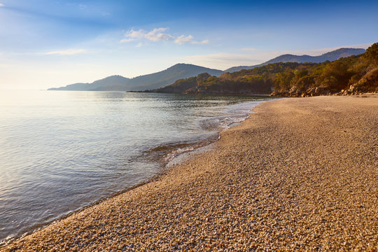 Amazing sunset view on Proti ammoudia beach near Olympiada town summer resort, Kavala region, Greece.. Incredibly romantic sunrise on the beach, Ionian Sea. View of the ocean. Tropical beach