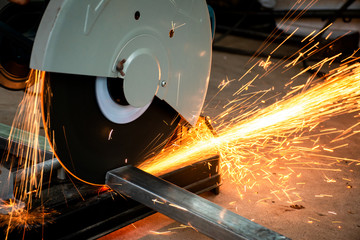 Steel cutter grinder are cutting iron pipe with bright sparks. - obrazy, fototapety, plakaty