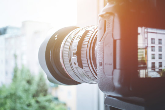 Surveillance And Stalking Concept: Camera With Telephoto Lens On Tripod, Observing A House