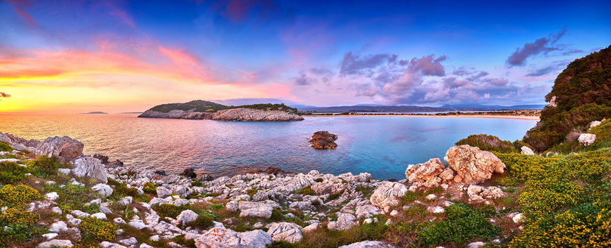 Amazing sunset view with multicolored clouds. Incredibly romantic sunrise on Voidokilia beach, Ionian Sea, Pilos town location, Greece, Europe. View of the ocean through the rocky shore